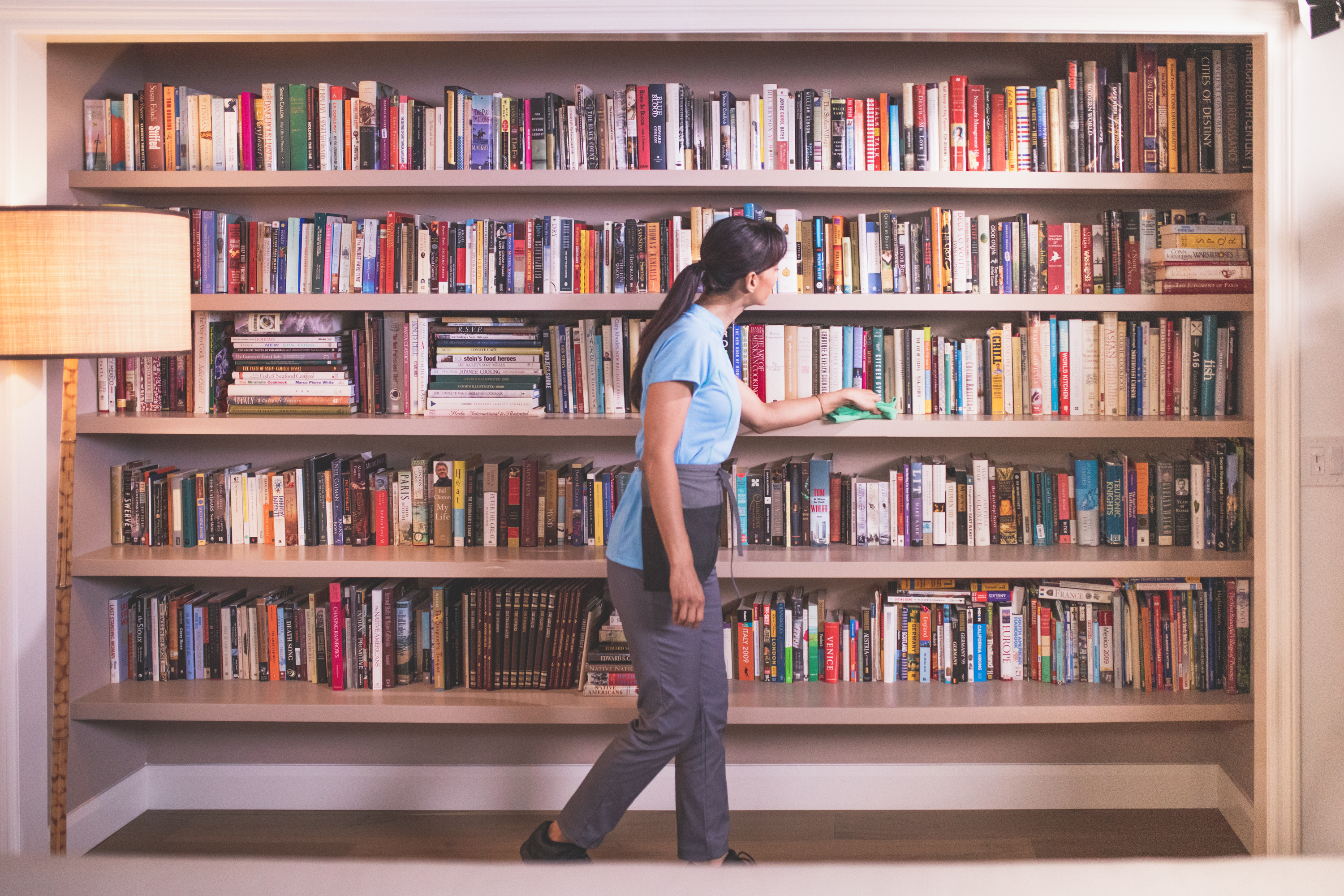 A Merry Maids of North DFW Area wiping down a bookshelf during small office cleaning services