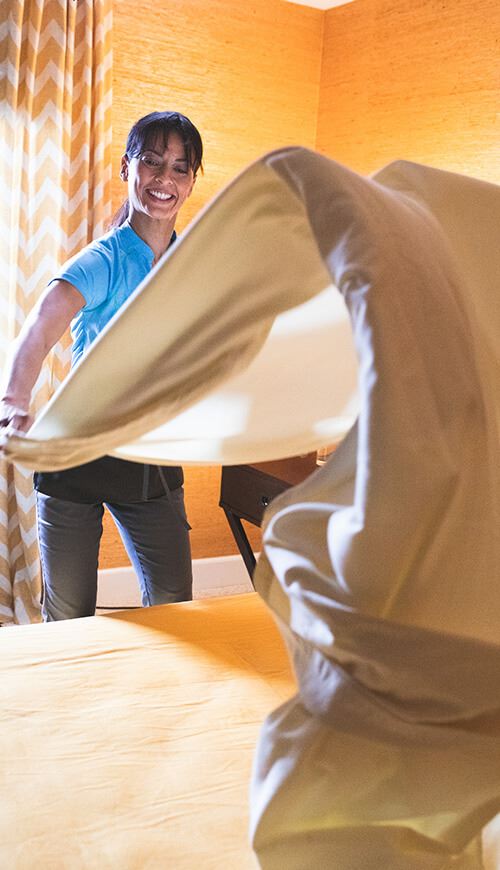 housekeeper making a bed 