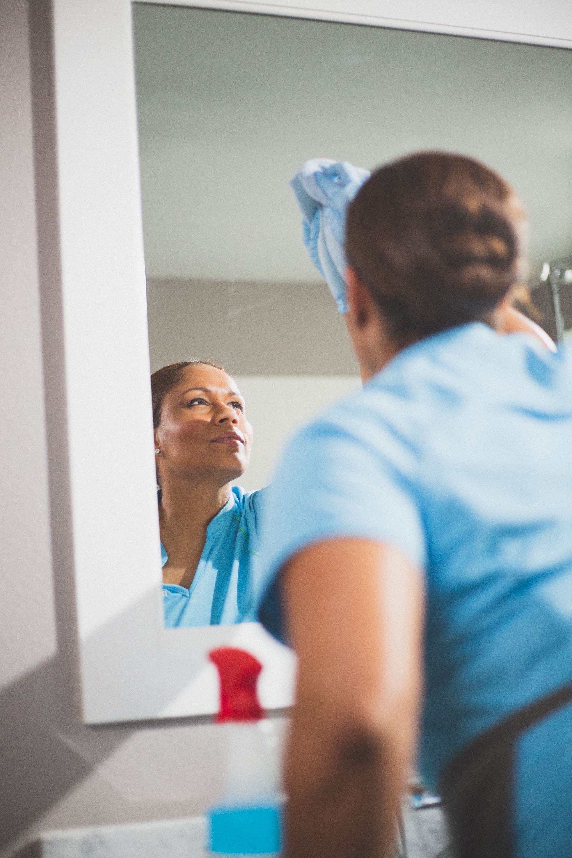 A Merry Maids team member disinfecting a bathroom mirror during move out cleaning services