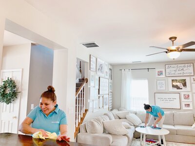 Two Merry Maids professionals cleaning a living room